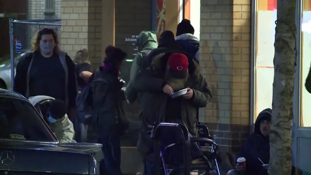 GROUP OF HOMELESS EATING OUTSIDE ON STREET