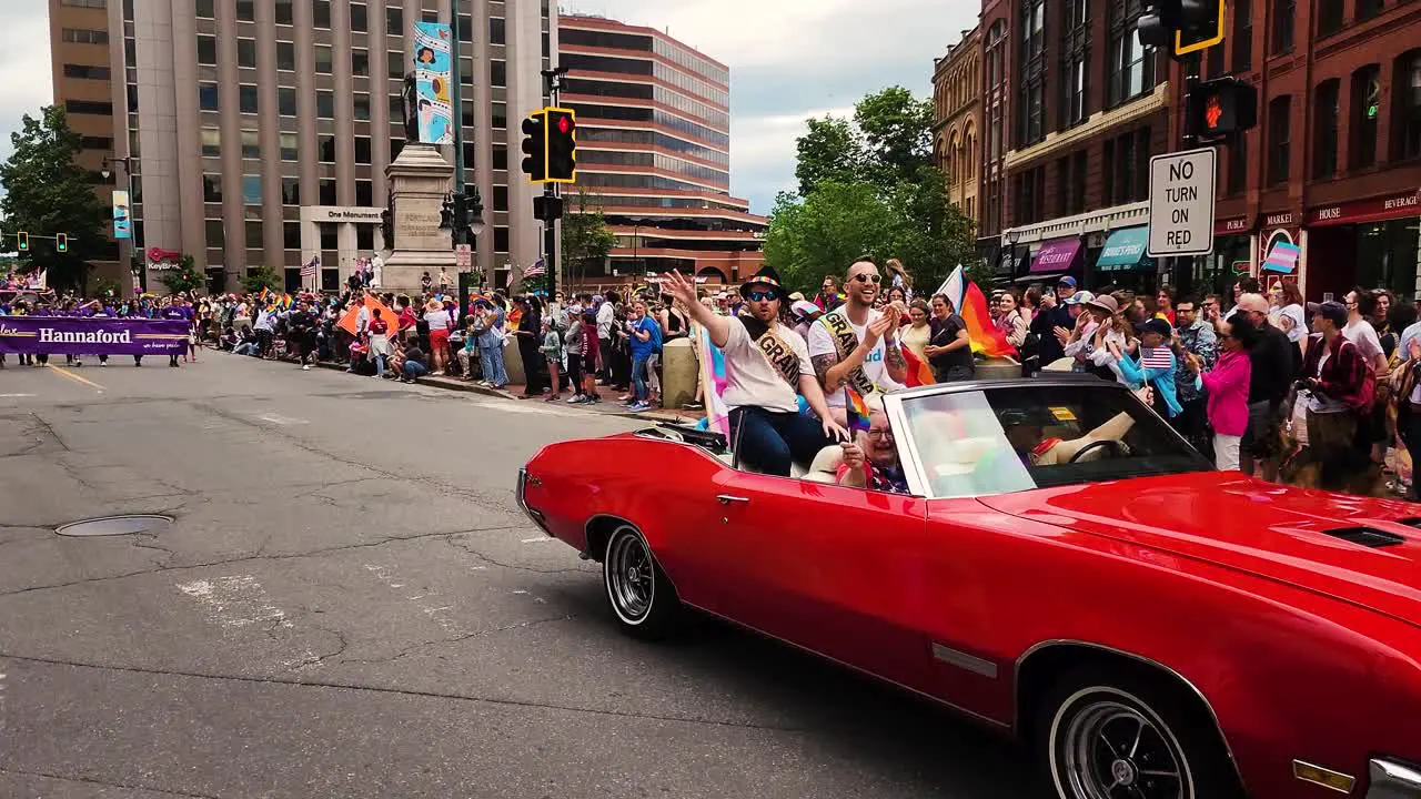 The Grand Marshals ride in a bright red convertible car in Gay Pride Paraade in Portland Maine