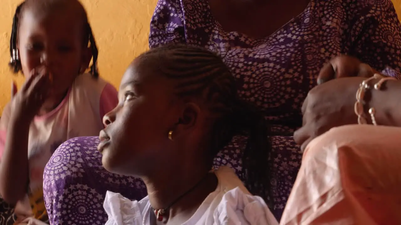 Two black women make braids with the hair of a girl