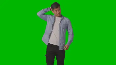 Studio Shot Of Casually Dressed Stressed Young Man Against Green Screen 