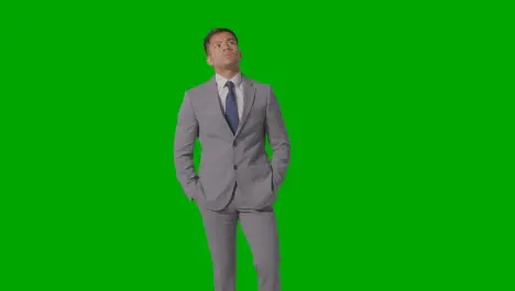 Three Quarter Length Portrait Of Serious Businessman In Suit Against Green Screen 