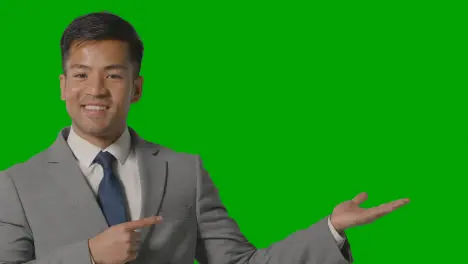 Smiling Businessman In Suit Presenting Or Showing Something Against Green Screen 