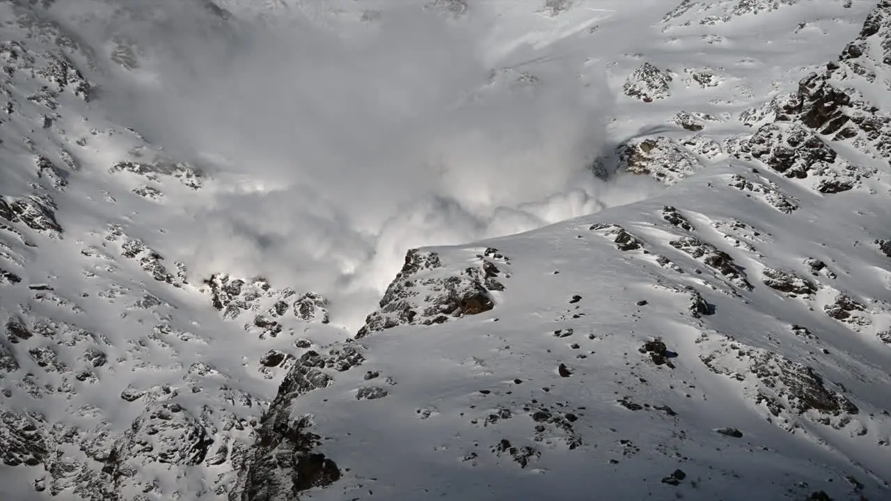 A large avalanche Made with power goes down a rocky Swiss alps Mountain next to ski slopes science