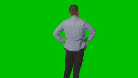 Three Quarter Length Studio Rear View Of Casually Dressed Young Man Looking At Green Screen 