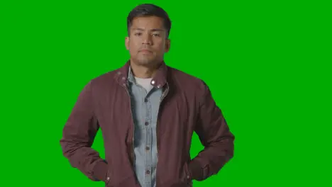 Portrait Of Casually Dressed Serious Young Man Against Green Screen 