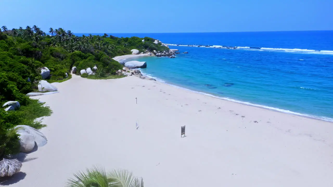 Flying over palm trees unveiling the white sanded Beach of Tayrona national park in Santa Marta Colombia