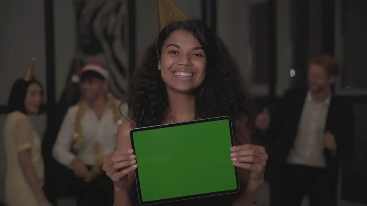 Young Happy Black Woman Holding A Tablet With Mockup Green Screen And Looking At The Camera At New Year's Eve Party