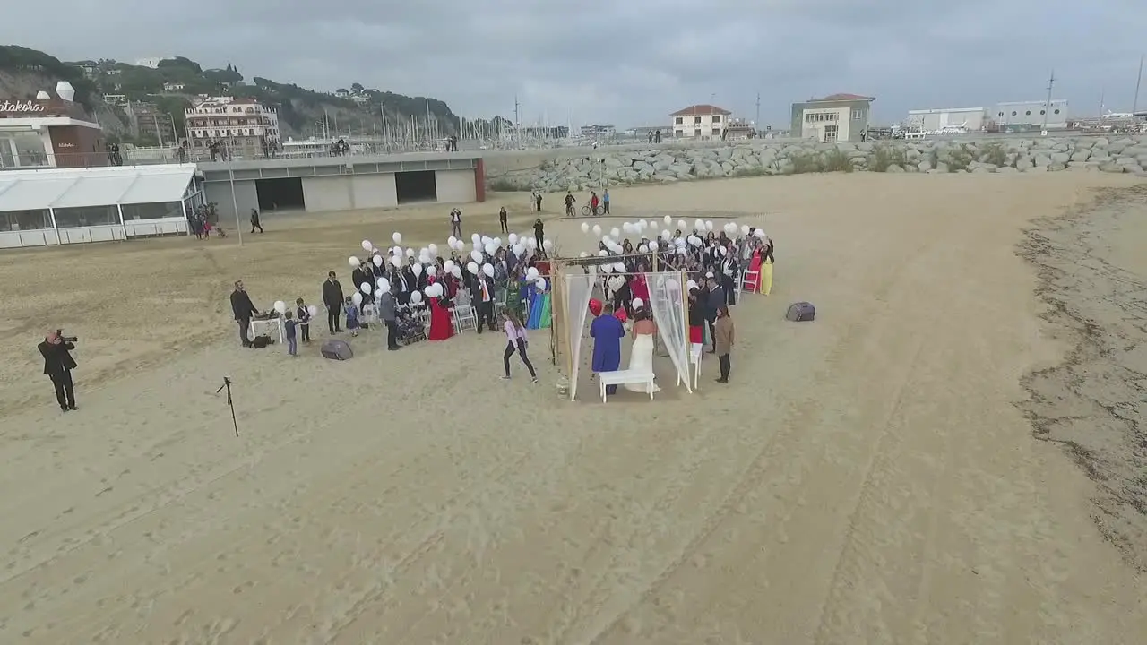 Aerial view of romantic beach wedding with guests holding white balloons Spain