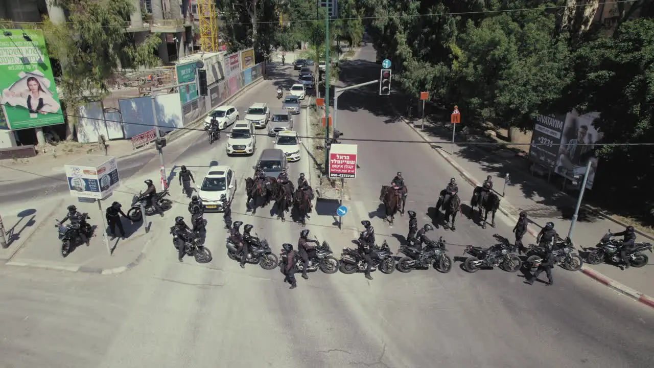 Police officers with horses and motorcycles are blocking a road against Israeli citizens protesting against the government