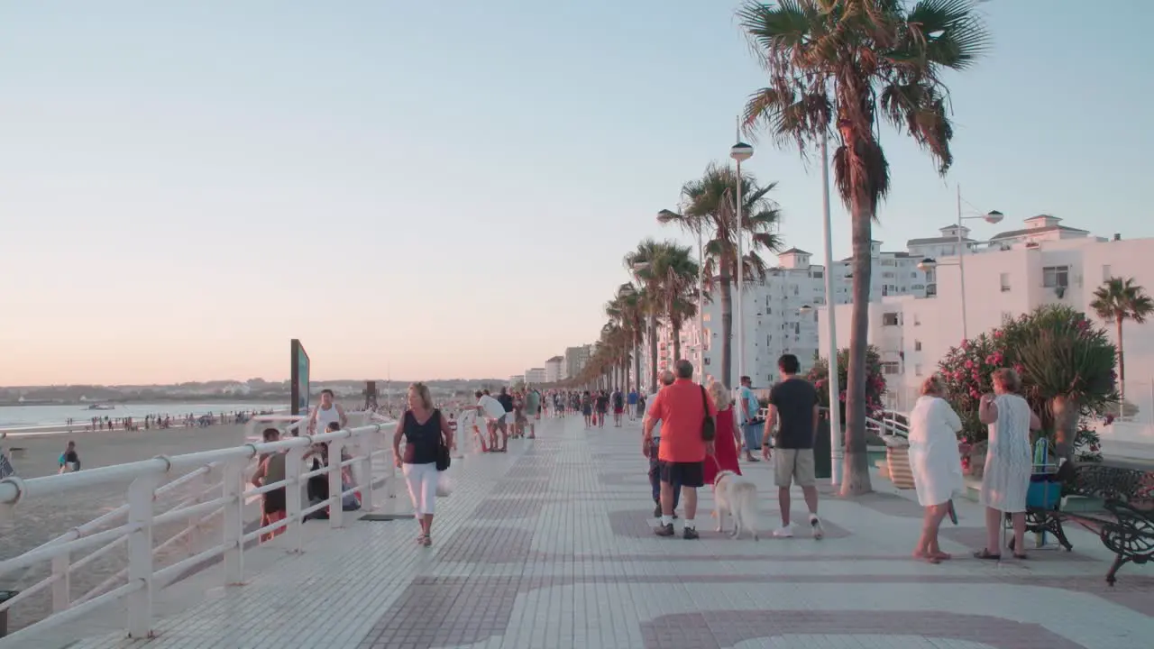 People walk along Valdelagrana Beach in Puerto Santa Maria Spain at sunset