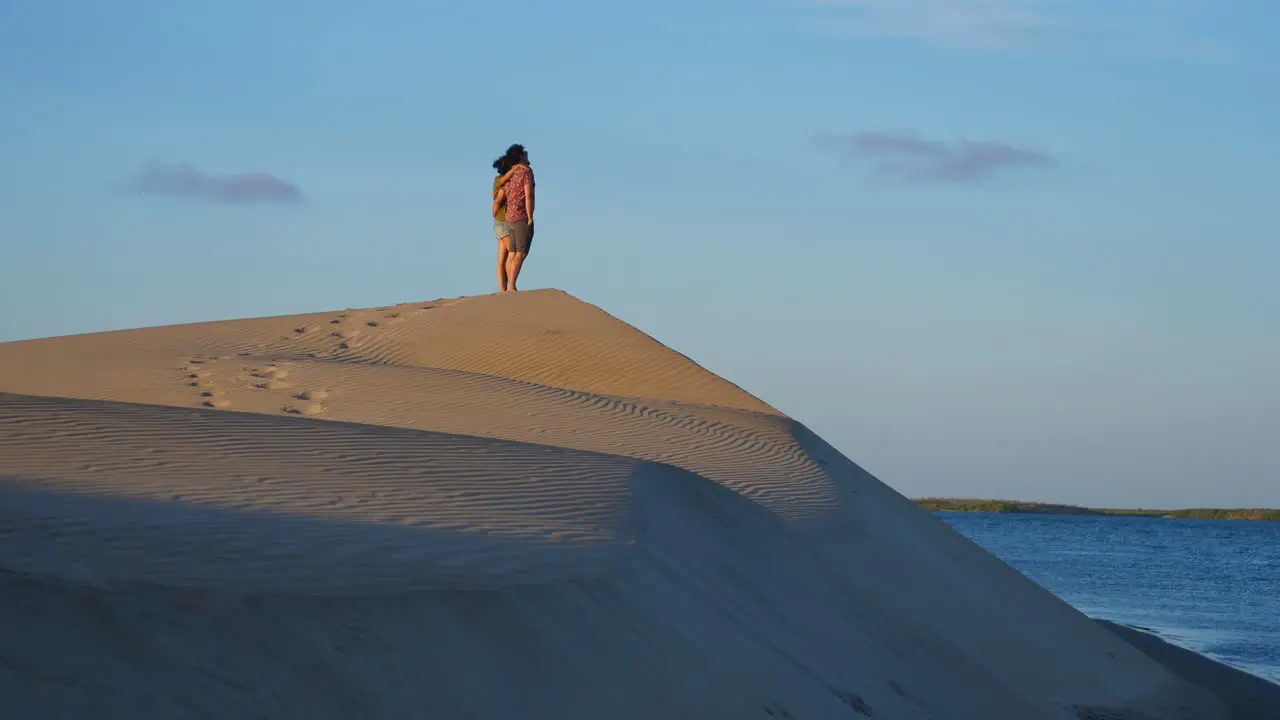 Establishing shot couple standing on the top Desert hill in Adolfo Lopez Mateos Baja California sur Mexico Sunrise in the background