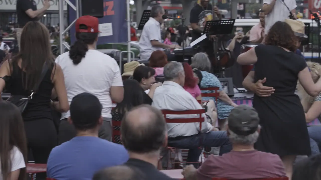 Static shot of people dancing together with a live band playing in the background