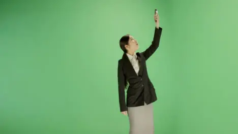 Businesswoman trying find phone signal on green screen