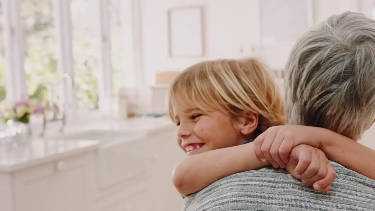 Child smile and hug grandmother in kitchen