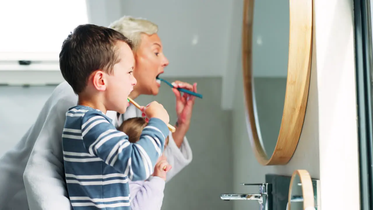 Mother boy child and brushing teeth in mirror