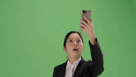 CU Businesswoman trying find phone signal on green screen