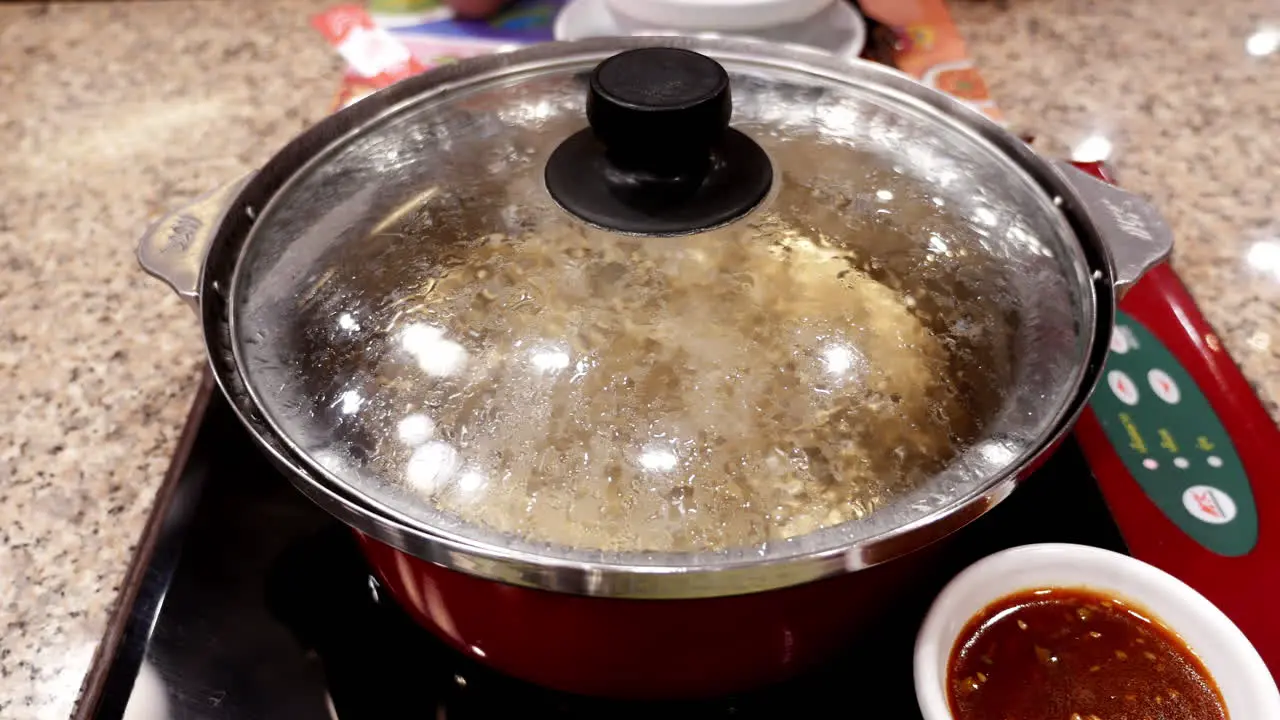 Preparing boiling water for cooking in a hot pot some Sukiyaki soup a mixture of vegetables and different kinds of meat in a restaurant in Bangkok Thailand