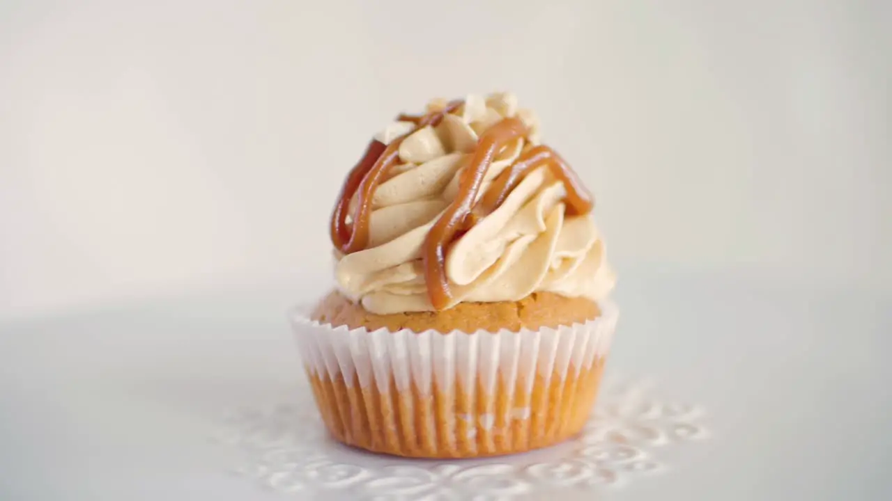 One peanut flavor cupcake rotating slowly on white decorated plate front