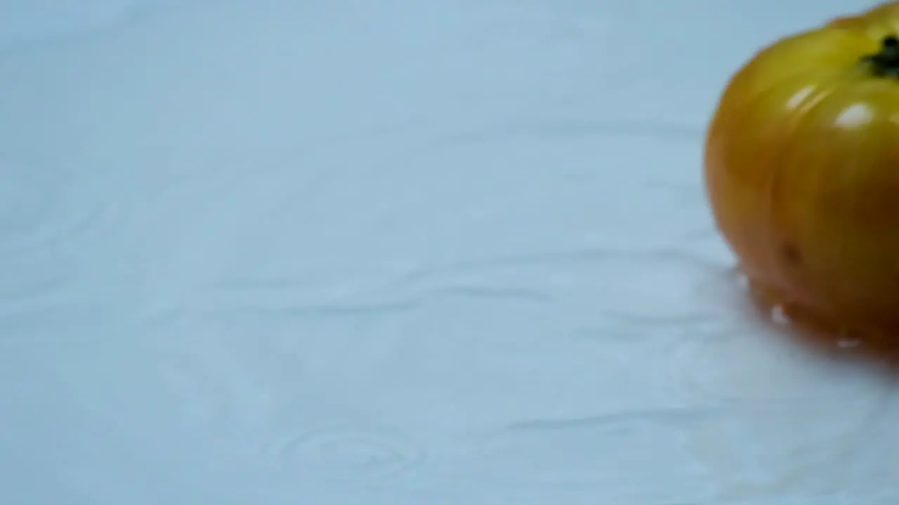 Super Slow Motion Tomato Cascading onto Water-Drenched Table