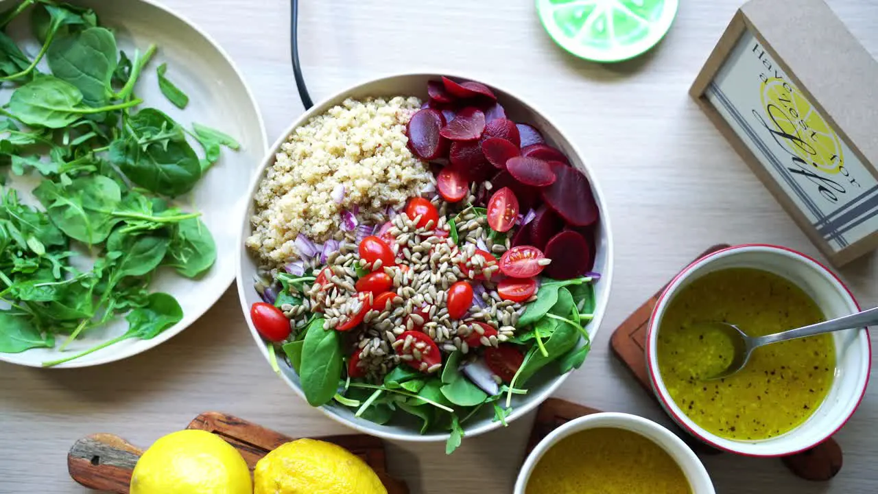 Aerial view of salad spinning on rotating platform pumpkin seeds quinoa beets tomatoes spinach leaf dressing