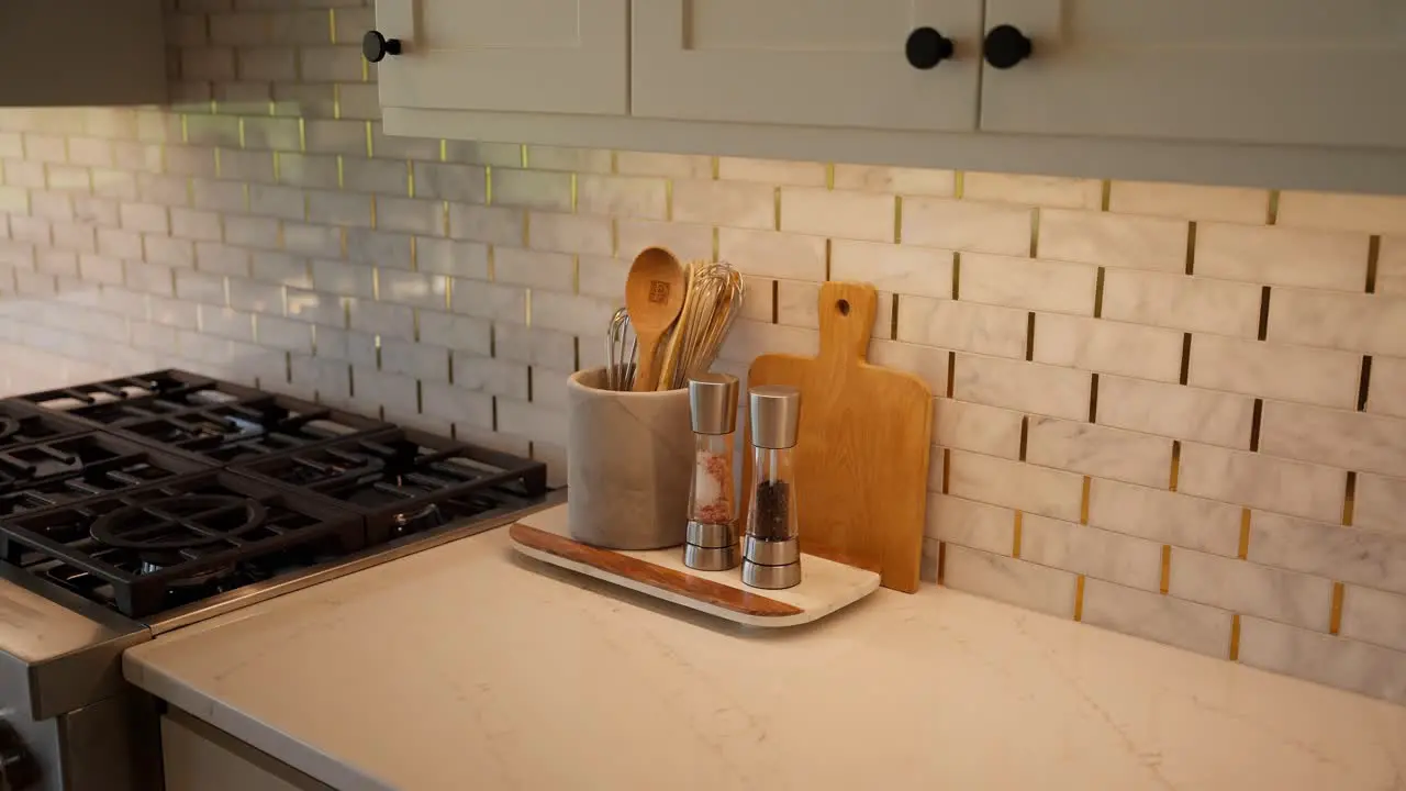 Close-up of cooking utensils cutting board salt and pepper shaker on kitchen countertop near stove