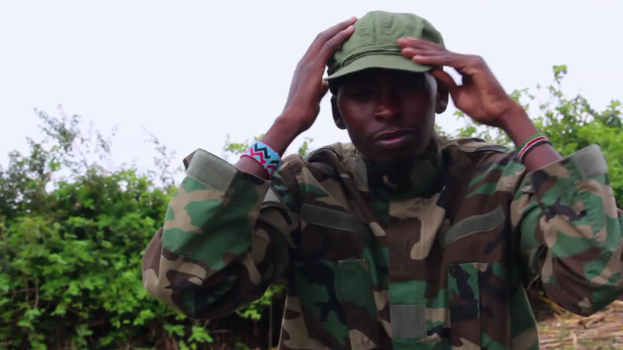 Sad army man sitting in Jungle fixing hat and puts hands on face cloudy day