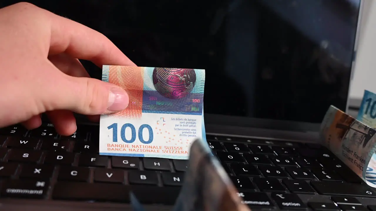 An electronical device user who made an online business shows bank notes over his laptop keyboard