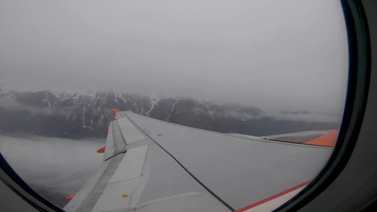 View out window as aeroplane takes off over snowy mountains Innsbruck Austria