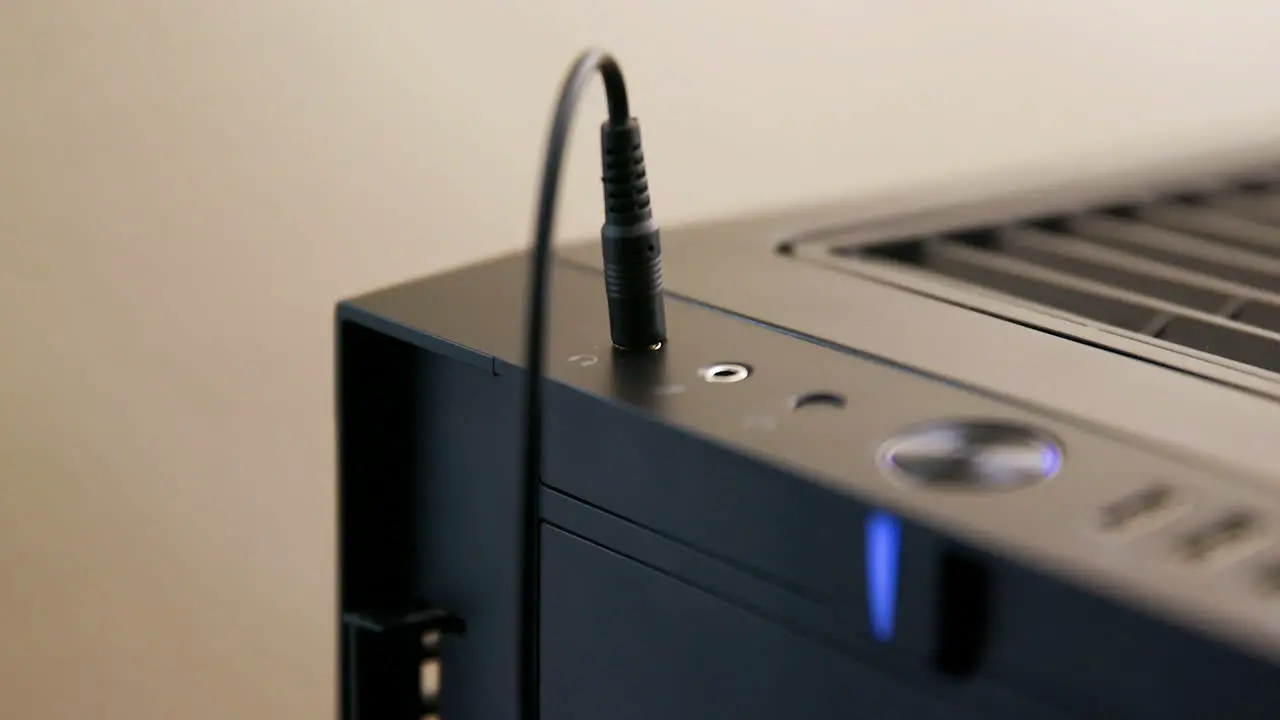 Man Plugs then Unplugs Headphone Cable into Jack on Desktop Computer