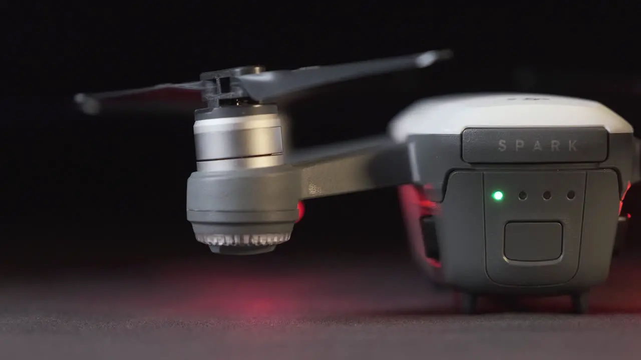 Track across the rear and propellers of a white DJI Spark drone with drone lights flashing