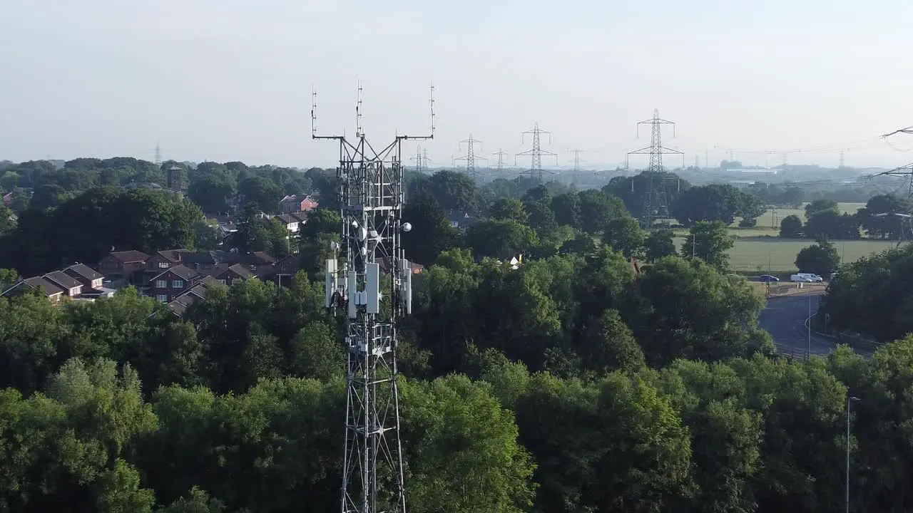 5G broadcasting tower antenna in British countryside with vehicles travelling on highway background aerial push in left view