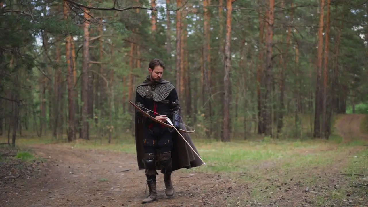 Man wearing costume of medieval warrior with bow in forest