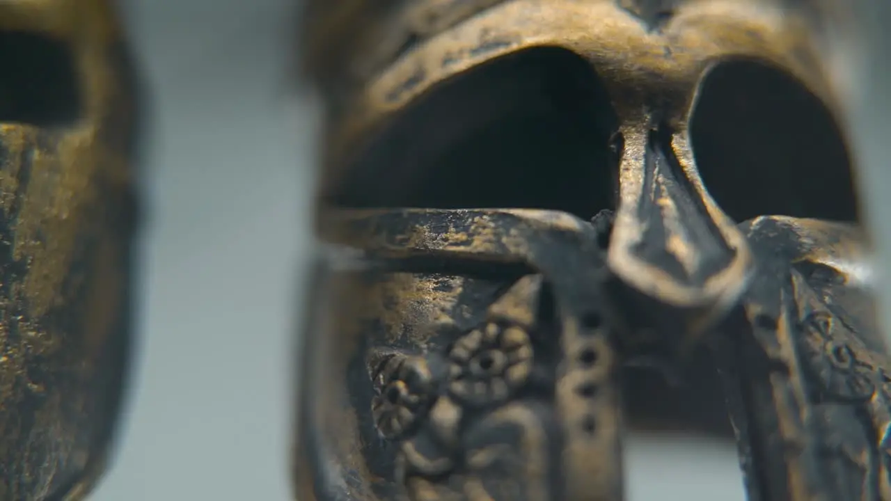 A zoom-in macro shot of a Spartan design two different ancient warrior metal bronze helmets textured shapes studio lighting Full HD cinematic video hyper Slow Motion 120 fps pan right