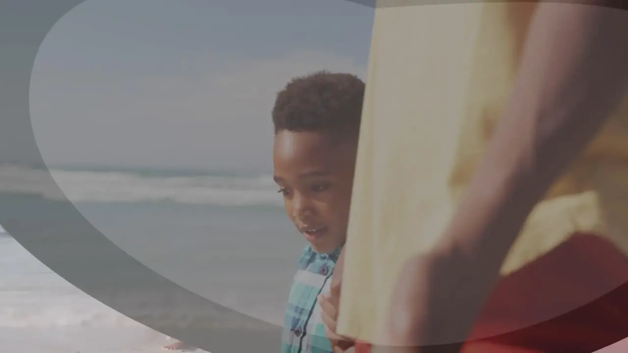 Animation of shapes over african american man and his son at beach