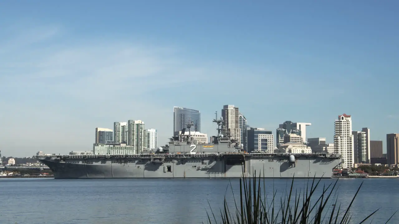 Large Naval battleship passing by Downtown San Diego skyline background cityscape