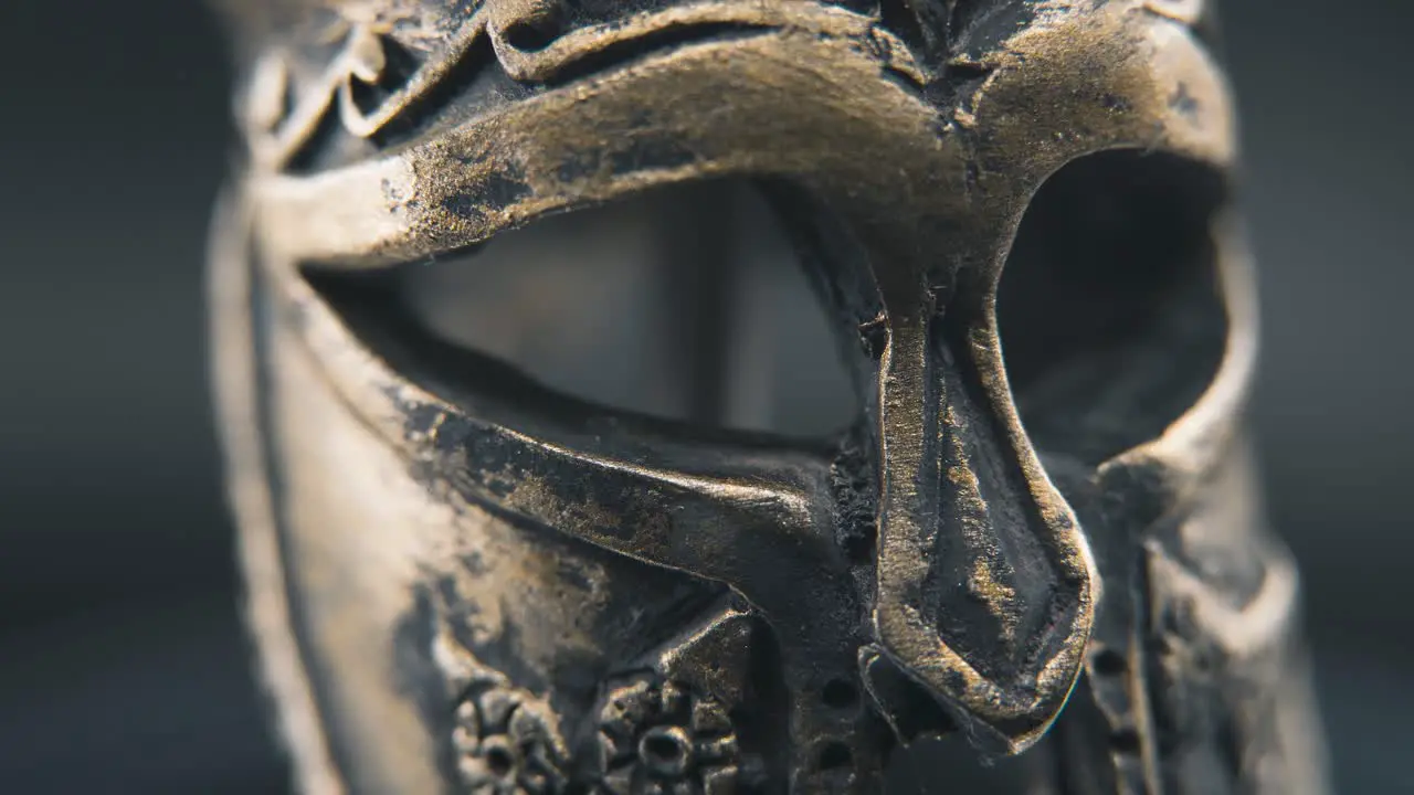 A close up macro professional slow pan right shot of a spartan face design warrior ancient greek bronze helmet on a 360 rotating stand studio lighting 4K smooth movement