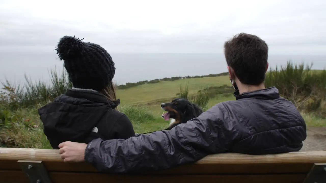 Couple sit on bench with dog at Ebey's Landing on Whidbey Island