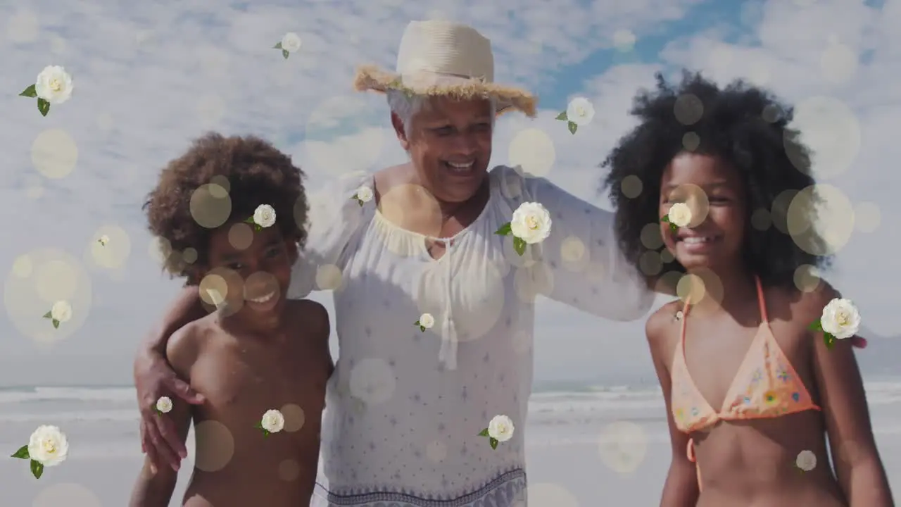 Animation of spots and flowers over happy african american grandmother and grandchildren on beach