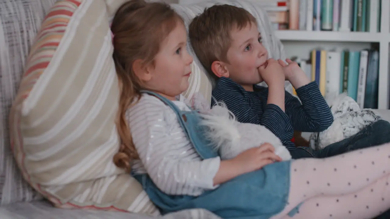 funny little boy and girl sitting on sofa at home brother and sister having fun making jokes being silly 4k