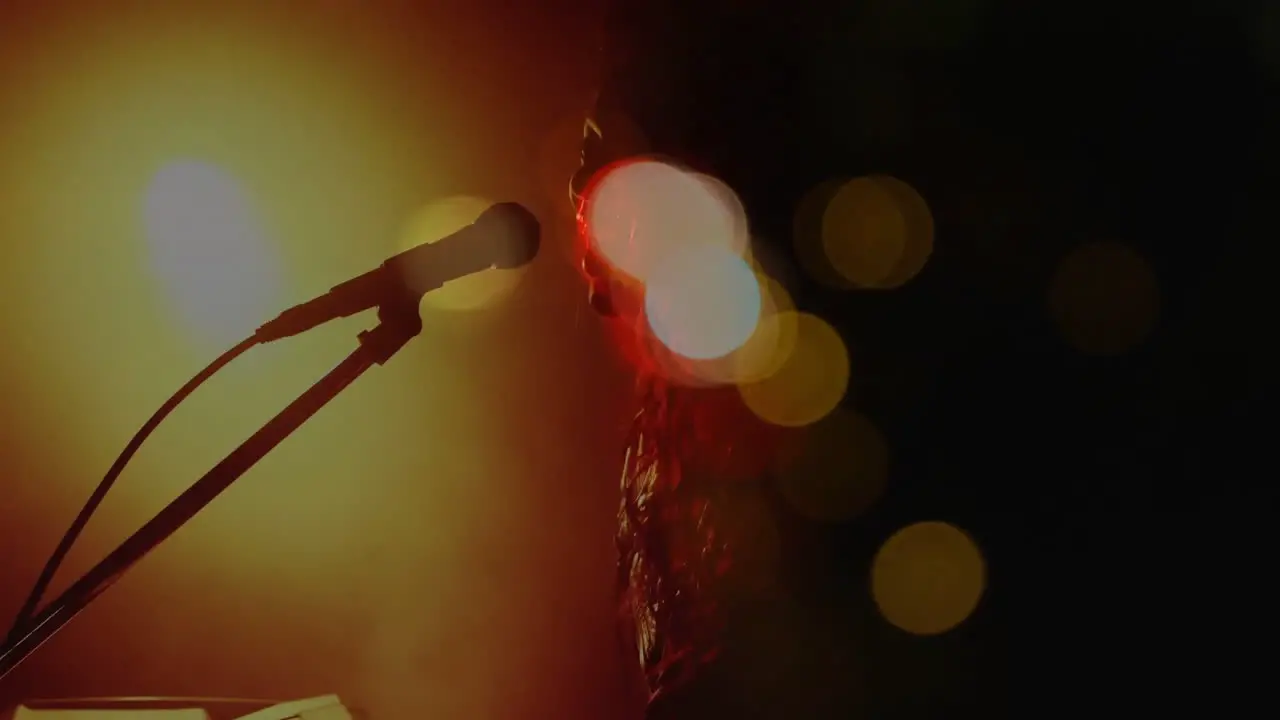 Caucasian female singer singing and playing keyboard during concert over light spots