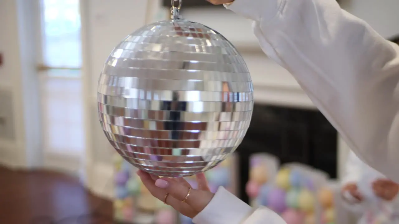 Spinning shiny silver disco ball in hand and preparing room for party