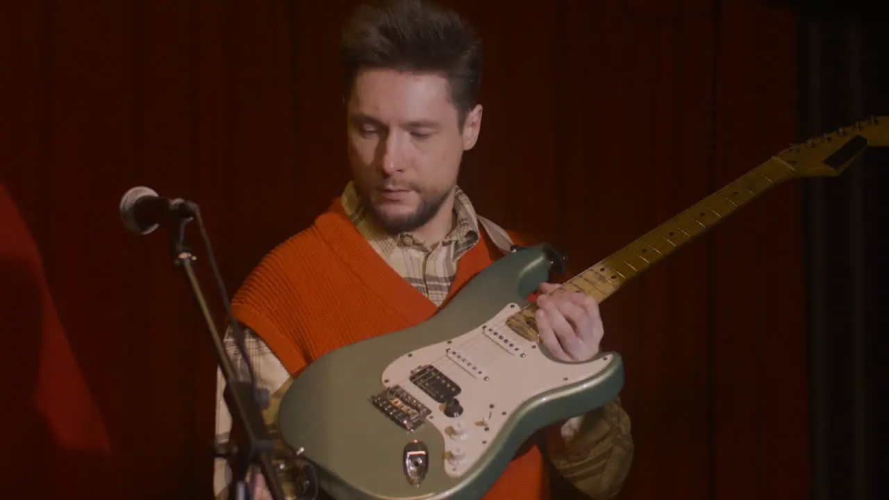 Male Guitarist Plugging Jack Into Electric Guitar And Tuning Before Live Performance