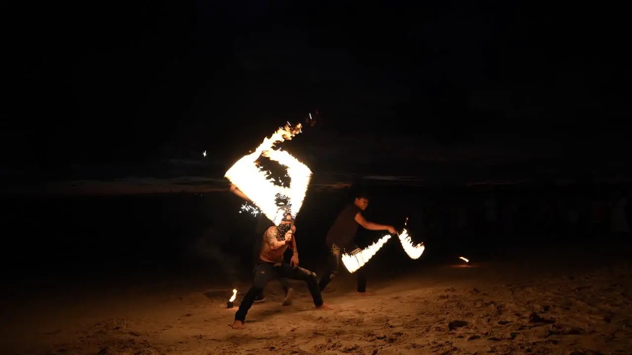 Fire dancers perform a night show on a sandy beach in Krabi Thailand with dynamic flames against dark backdrop