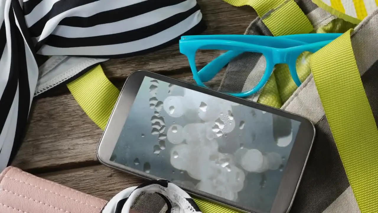 Smartphone with flickering spots of light over glasses and travel items