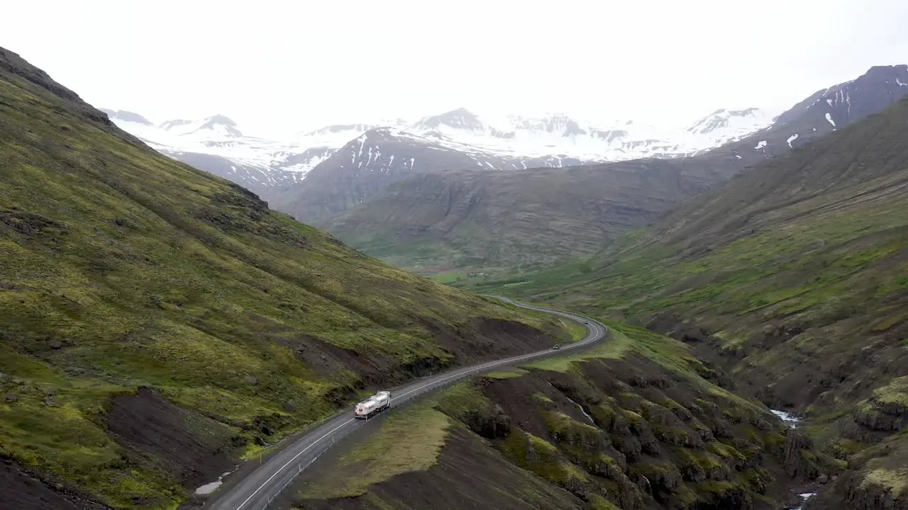 Semi truck driving through mountains in Iceland with drone video moving behind