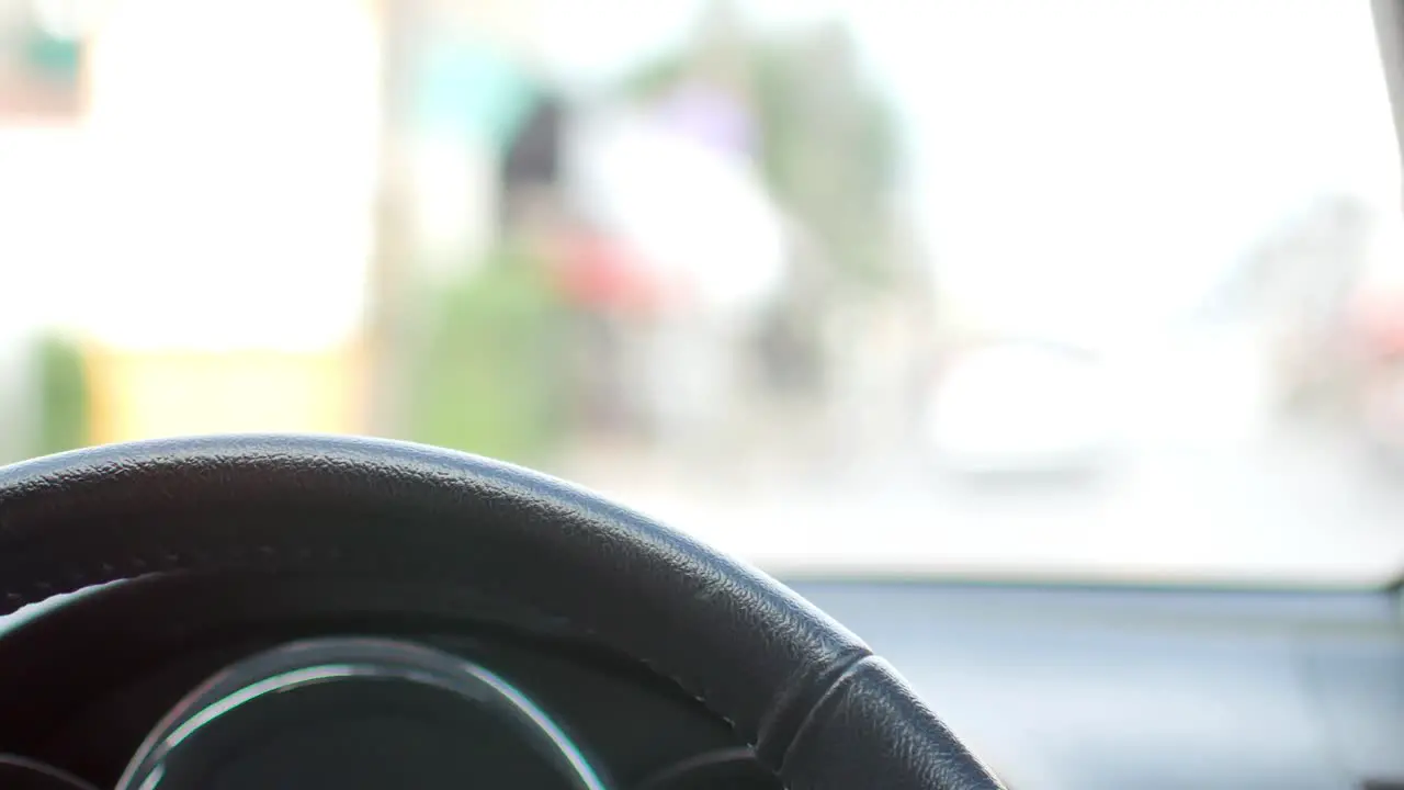 POV to the car steering wheel while driving on the road in soft focusing