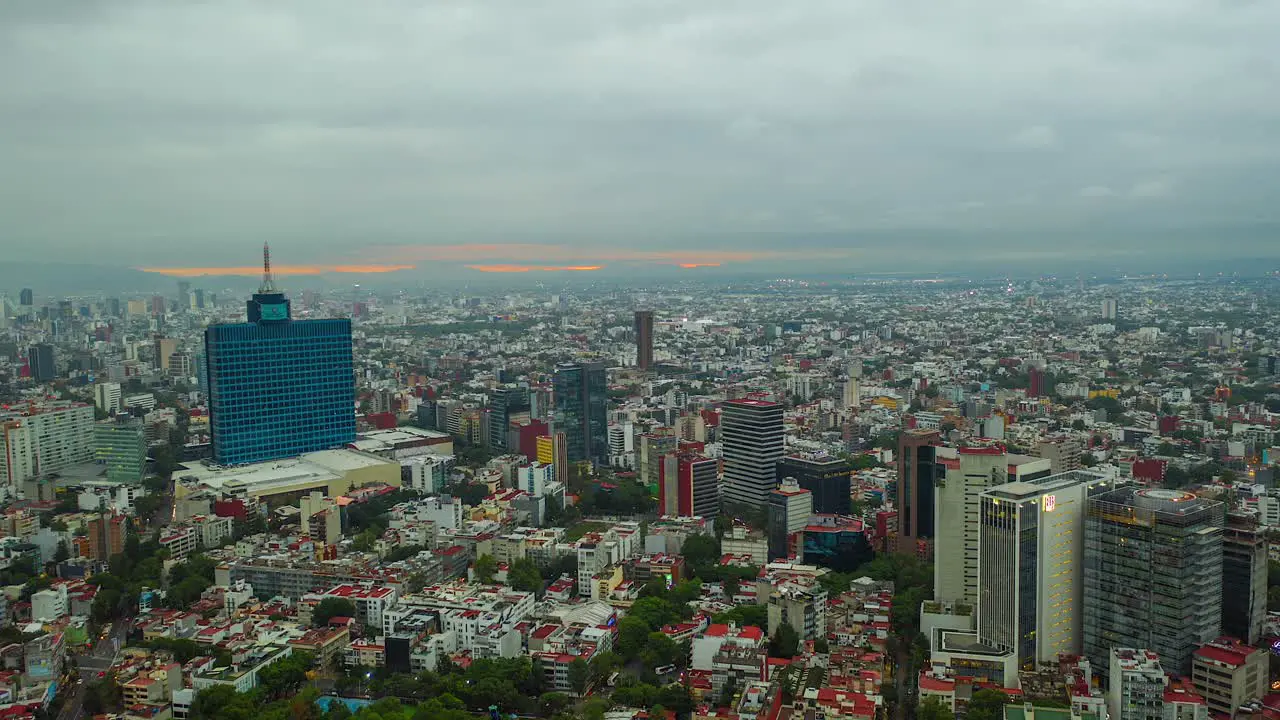 Aerial moving time lapse view of overcast clouds moving over the city revealing a colorful sunrise sky in Mexico America Reverse hyperlapse drone shot