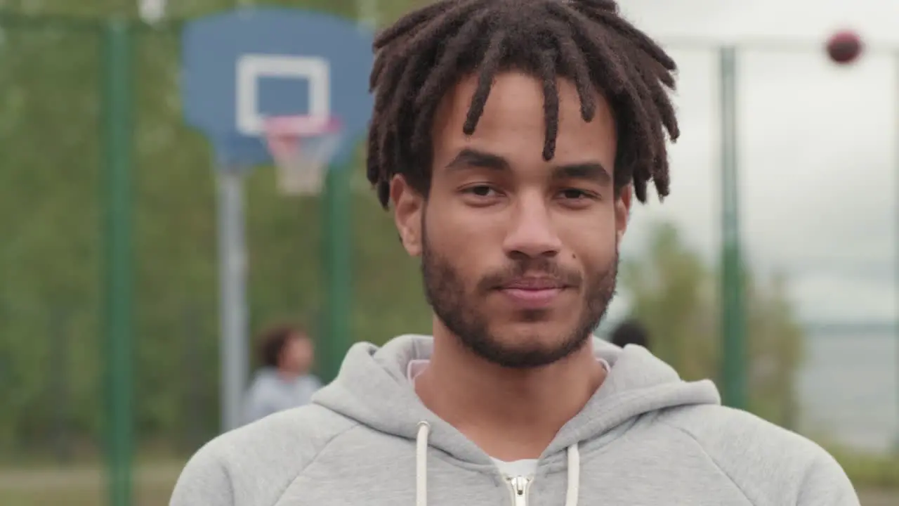 Young Smiling Afroamerican Athlete With Dreadlocks Holding Ball For Playing Basketball In Basketball Court