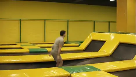 Athletic male performs back double somersault flawlessly jumping on trampoline