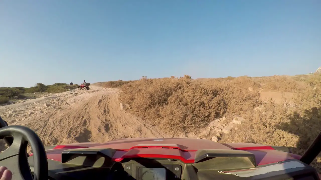 Point of view driving a dune buggy on Cavo Greco trails in rough terrain and almost gets stuck